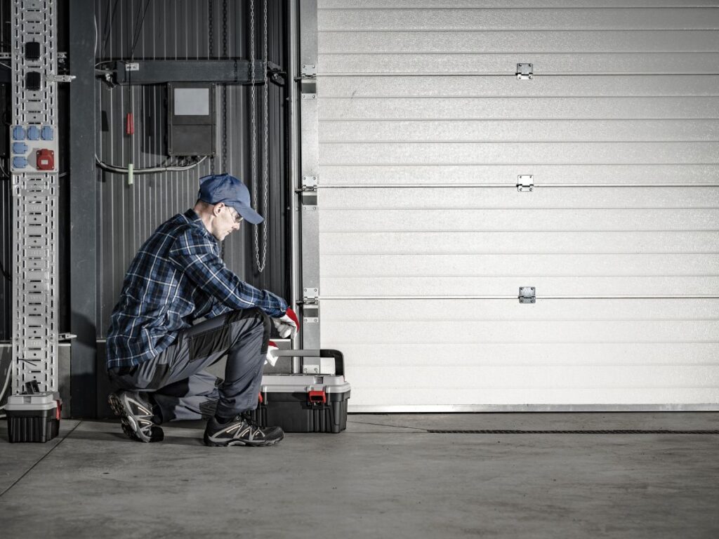 Commercial technician inspecting a large overhead garage door.