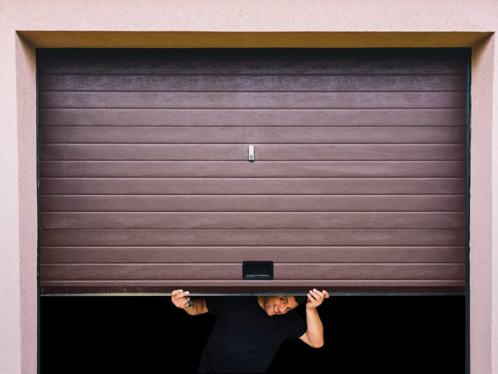 Man manually lifting a garage door from underneath.