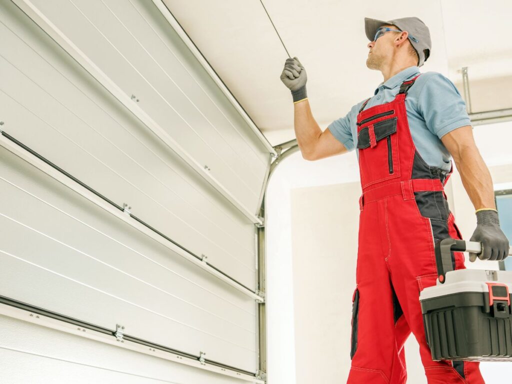 Technician holding toolbox while checking a garage door release cord.